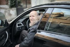 an old man sitting in the driver's seat of a car