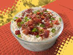 a bowl of food with bacon and green onions in it sitting on a red table