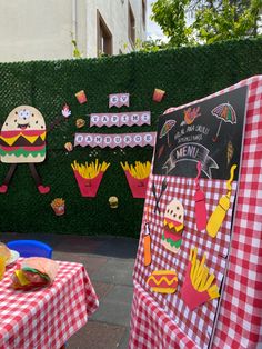 a table topped with food next to a green wall covered in paper cutout art