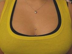 a woman wearing a yellow tank top with a heart shaped necklace on her left chest