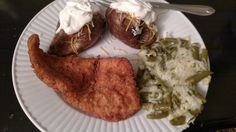 a white plate topped with fried chicken, potatoes and mashed potatoes next to green beans