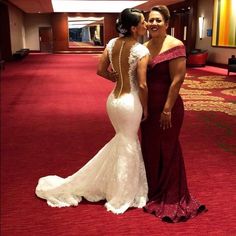 two women in dresses standing next to each other on a red carpeted room floor