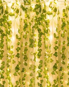 the curtain is covered with green leaves and fairy lights