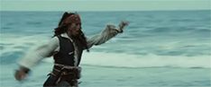 a man dressed as captain jack sparrow running on the beach with his arms in the air