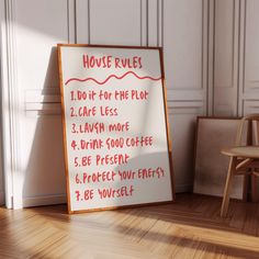 a house rules sign sitting on the floor next to a wooden chair and wall with white paneling