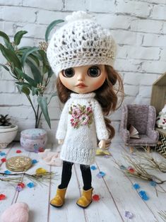 the doll is wearing a white sweater and hat