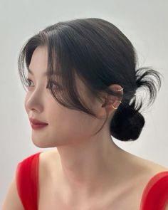 a woman in a red dress is looking off to the side with her hair pulled back