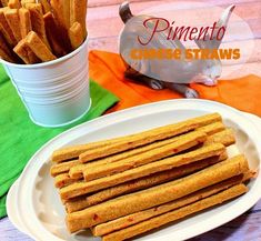 there is a white plate topped with cheesy sticks next to a cup and napkin