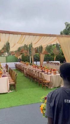 a man standing in front of a long table with flowers on it and chairs around it