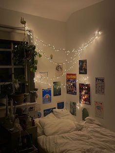 an unmade bed with lights strung from the ceiling