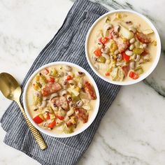 two bowls filled with soup sitting on top of a blue towel next to a gold spoon