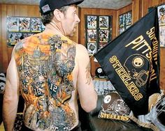 a man with tattoos on his back holding up a black flag and wearing a baseball cap