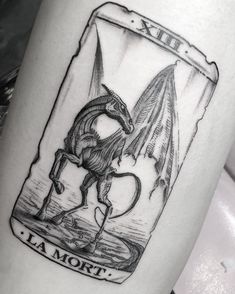 a black and white photo of a tattoo with a dragon on it's leg