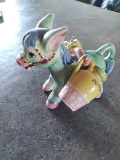 a ceramic figurine of a dog holding a cup sitting on a counter top