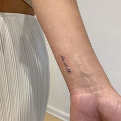 a woman's wrist tattoo with the word love written in cursive writing