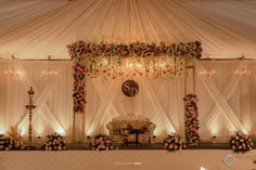 a decorated stage with flowers, candles and chandelier for a wedding or reception