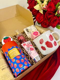 an open box filled with lots of different items next to a bouquet of red roses