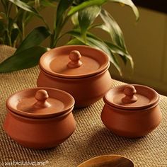 three brown pots and spoons sitting on a table