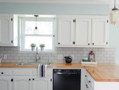 a kitchen with white cabinets and wood counter tops, an oven and dishwasher