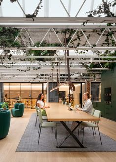 two people sitting at a table in the middle of a room with plants growing on the ceiling