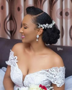 a woman in a wedding dress sitting on a couch holding a bouquet and looking off to the side