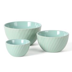 three bowls are sitting next to each other on a white surface, one is light green and the other is pale blue