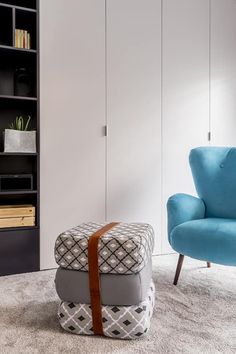 a living room with a blue chair and white bookcase next to it on the floor