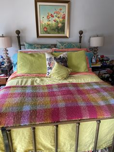 a bed with colorful bedspread and pillows on top of it in a bedroom