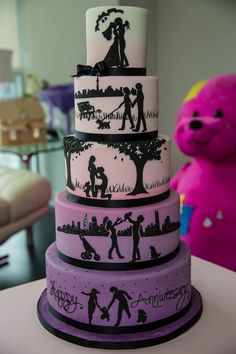 a wedding cake with silhouettes of people and trees on the bottom tier is next to a pink teddy bear