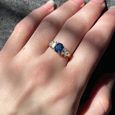 a woman's hand with a blue and white diamond ring on her left hand