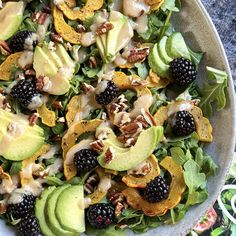 a salad with blackberries, avocado and nuts