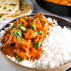 a bowl filled with white rice and chicken curry next to tortilla bread on the side