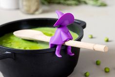 a purple figurine sitting on top of a wooden spoon in a black bowl