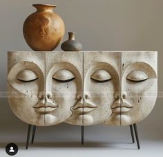 an artistic display with three faces and a vase on the top one is made out of concrete