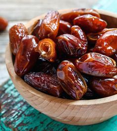 a wooden bowl filled with raisins sitting on top of a blue and green table