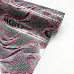 a close up of a tie on a white surface with pink, green and black swirls