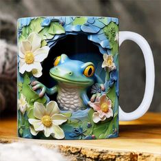 a ceramic mug with a blue frog and flowers on it