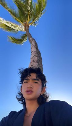 a young man standing under a palm tree