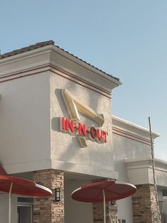 an in - n - out restaurant with red umbrellas and chairs outside the building