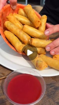 a plate with some food on it next to a bowl of sauce and two hands