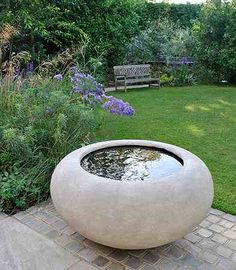 a garden with a pond and bench in the middle