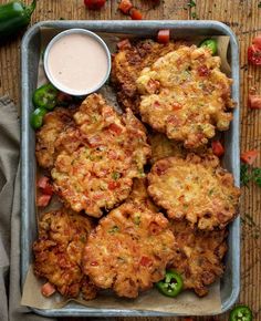 some fried food is on a tray with sauce and peppers next to the side dish