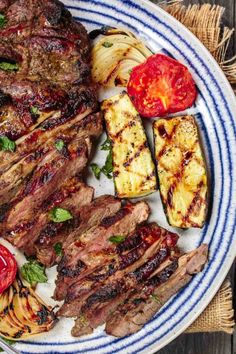 grilled steak and vegetables on a blue and white plate