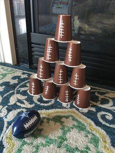 a bunch of cups sitting on top of a rug next to a football ball and a remote control