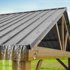 a metal roof with water coming out of the gutter and into the ground below