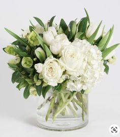 a vase filled with white flowers and greenery