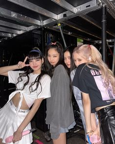 four young women posing for the camera in front of a metal rack with their hands on their hipss