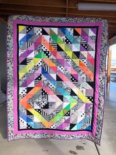 a colorful quilt hanging from the side of a building