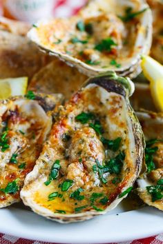 several oysters on a plate with lemon wedges and parsley garnish