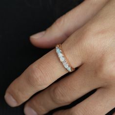 a woman's hand wearing a ring with opalite stones on the side